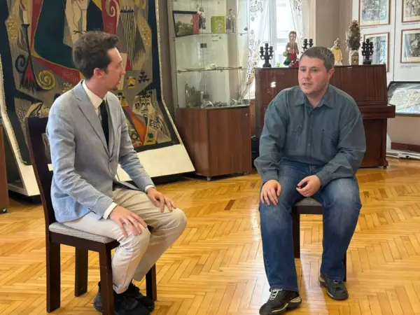 Два чоловіки сидять на стільцях і говорять