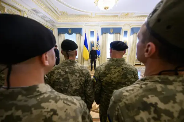 фото з-за спин воїнів, у далечині біля прапорів - президент України