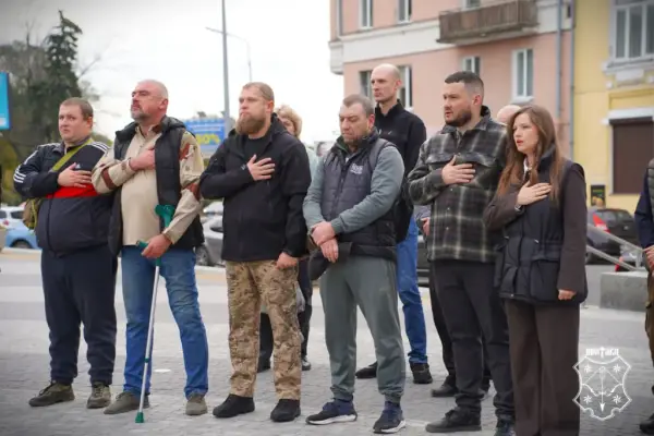 учасники заходу слухають гімн України, тримаючи праву руку біля серця